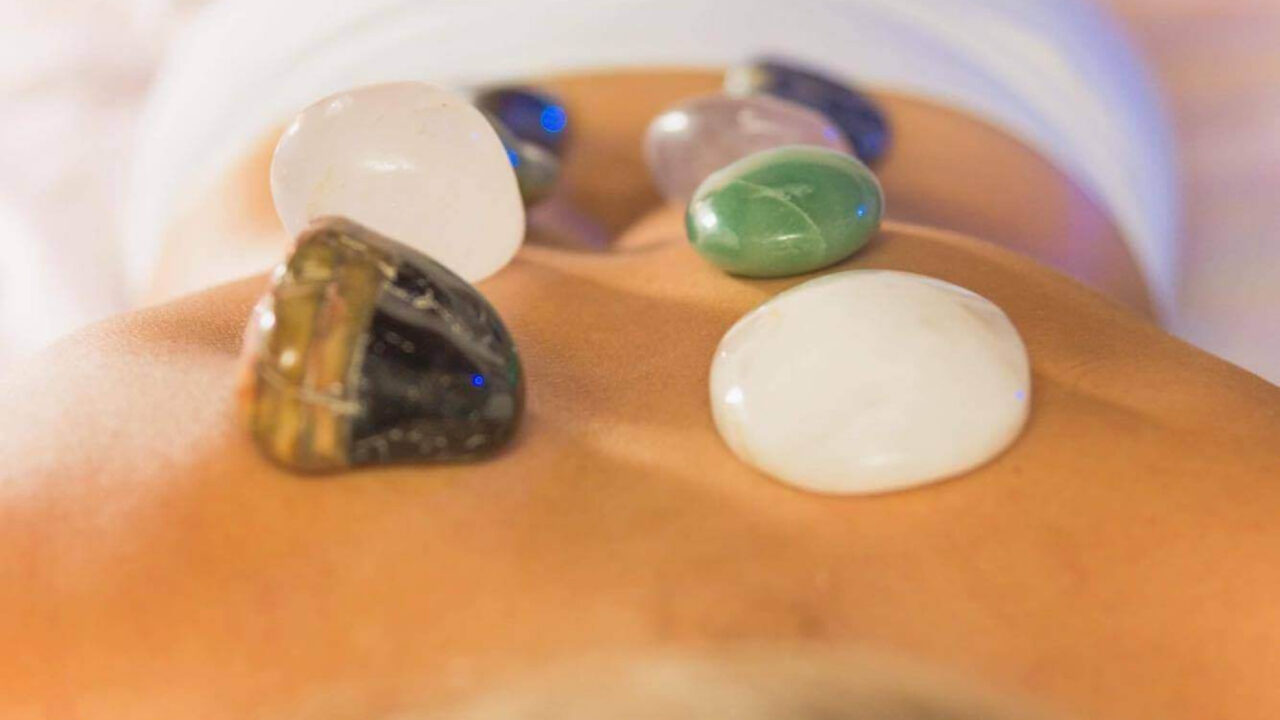 Pedras quentes posicionadas nas costas de uma mulher, proporcionando relaxamento profundo e alívio do estresse.