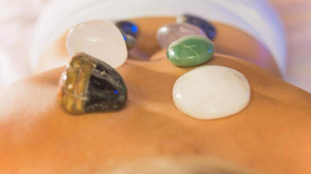 Pedras quentes posicionadas nas costas de uma mulher, proporcionando relaxamento profundo e alívio do estresse.