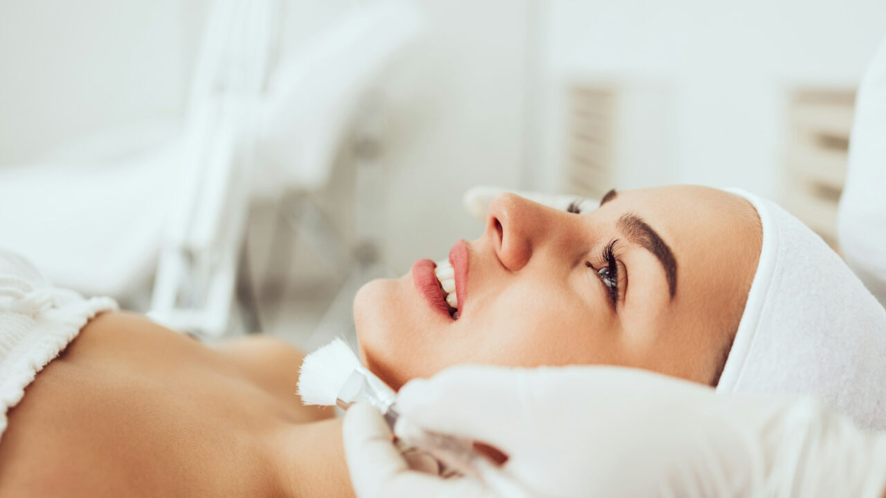 Mulher sorrindo enquanto recebe um procedimento de permanente de cílios, realçando a curvatura natural dos fios.