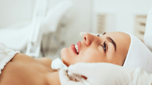 Mulher sorrindo enquanto recebe um procedimento de permanente de cílios, realçando a curvatura natural dos fios.